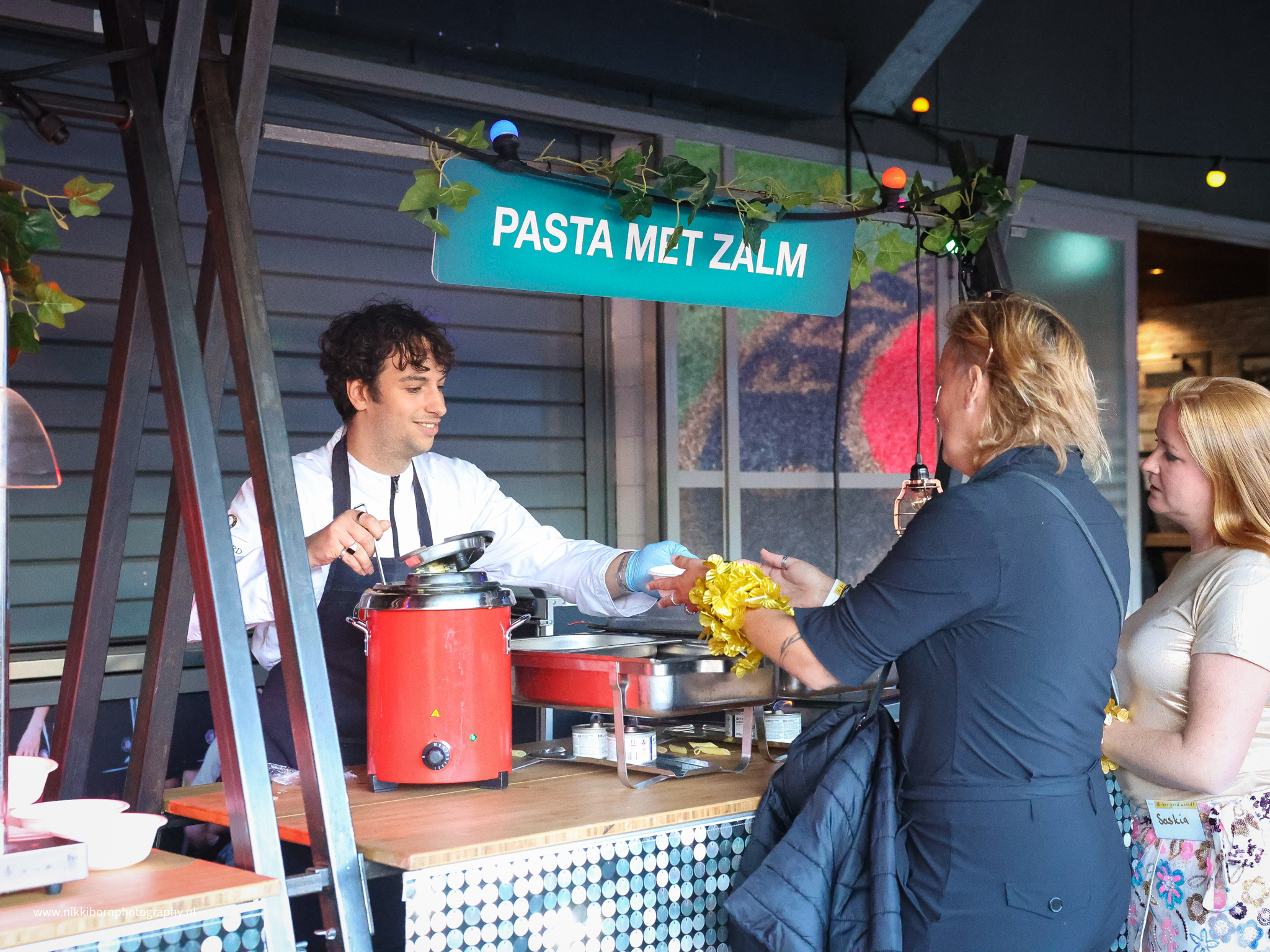 Man overhandigt pasta met zalm aan een vrouw - Timeless Events