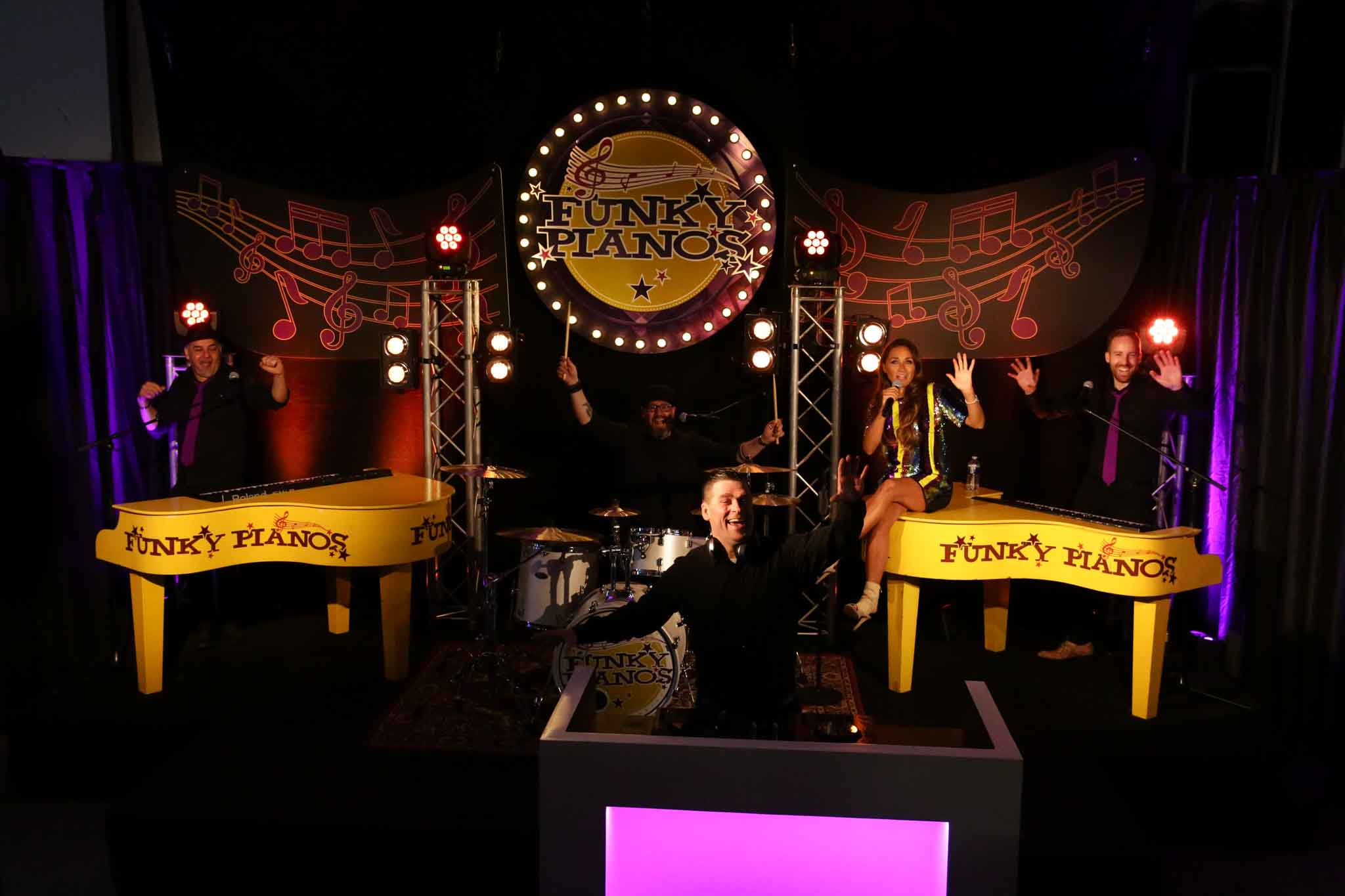 Funky Pianos met 5 personen op het podium zwaaiend naar de camera - Timeless Events
