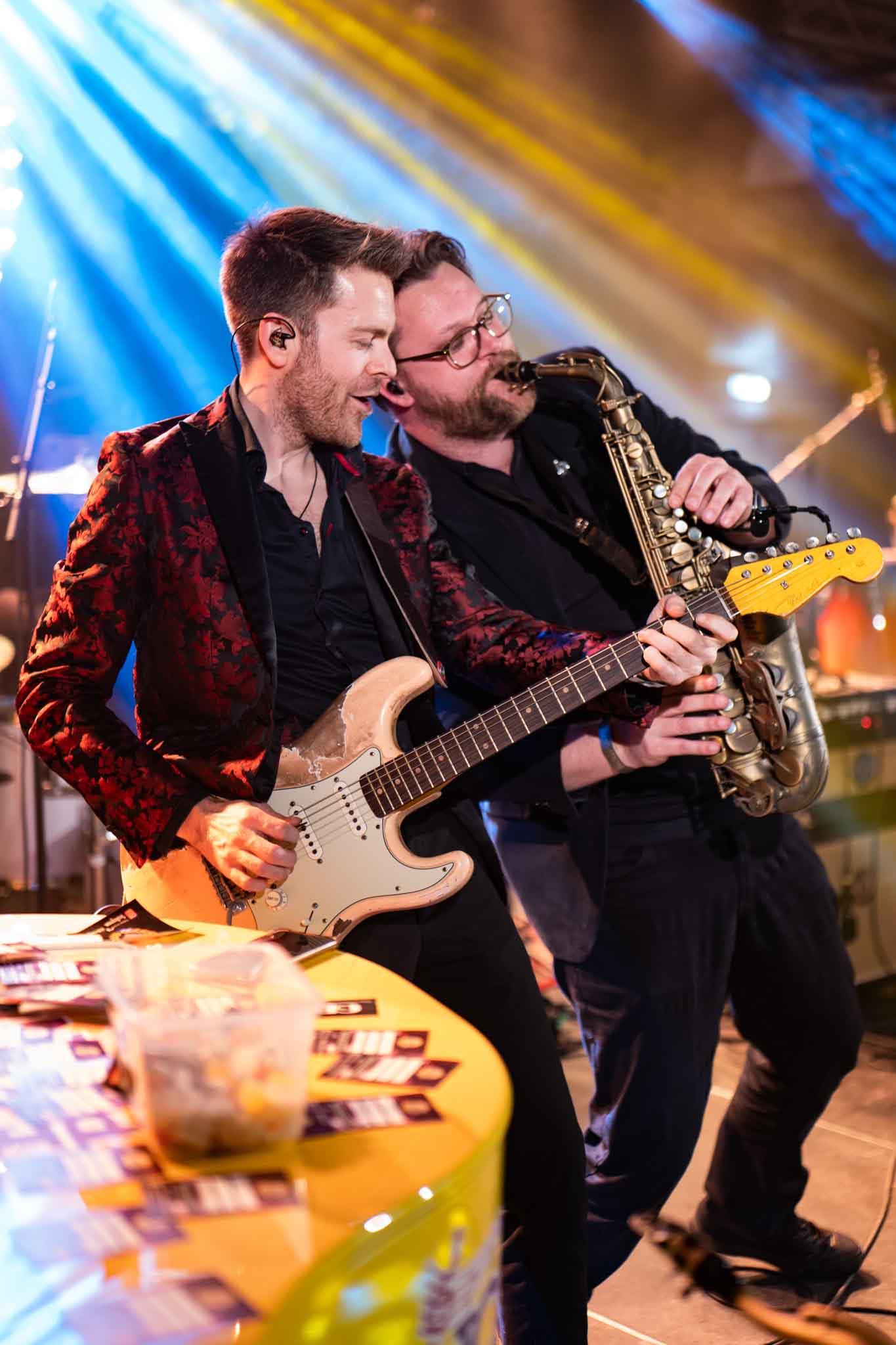 Een man speelt elektrisch gitaar naast een man blazend op de saxofoon - Timeless Events