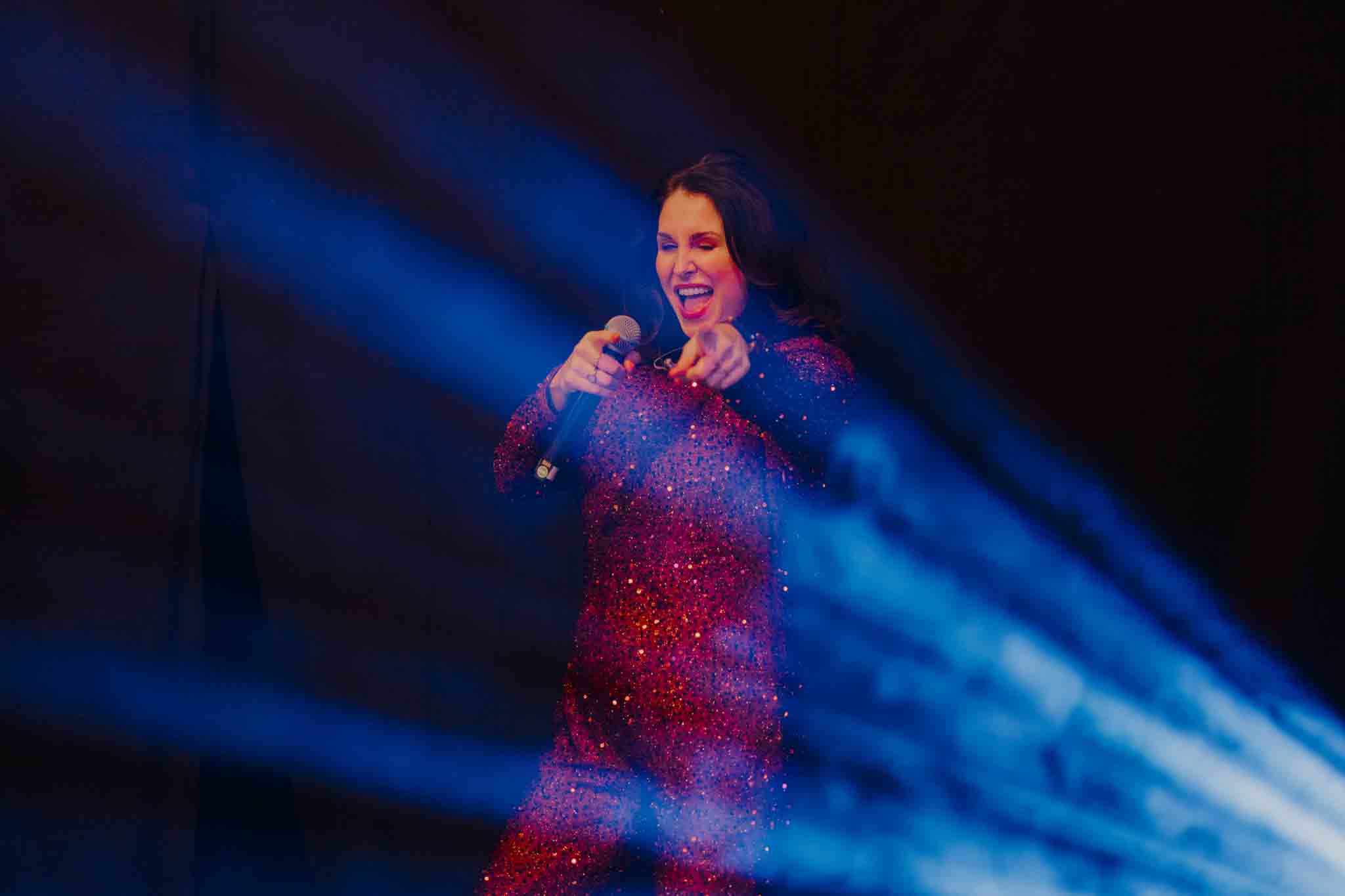 Ladies on Fire zangeres met microfoon en wijzend naar het publiek - Timeless Events