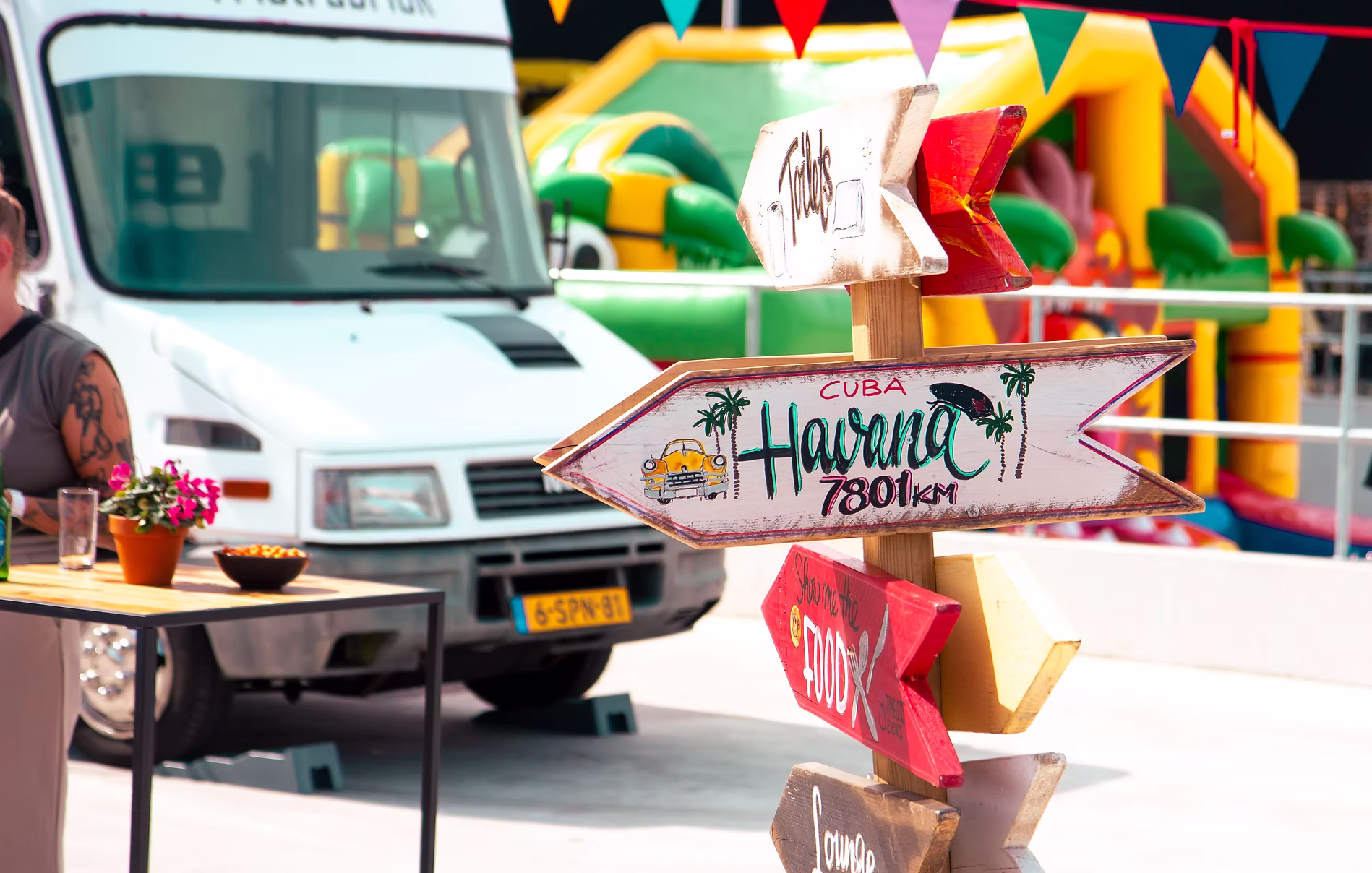 Bord met pijlen met op de achtergrond een bus en springkussen