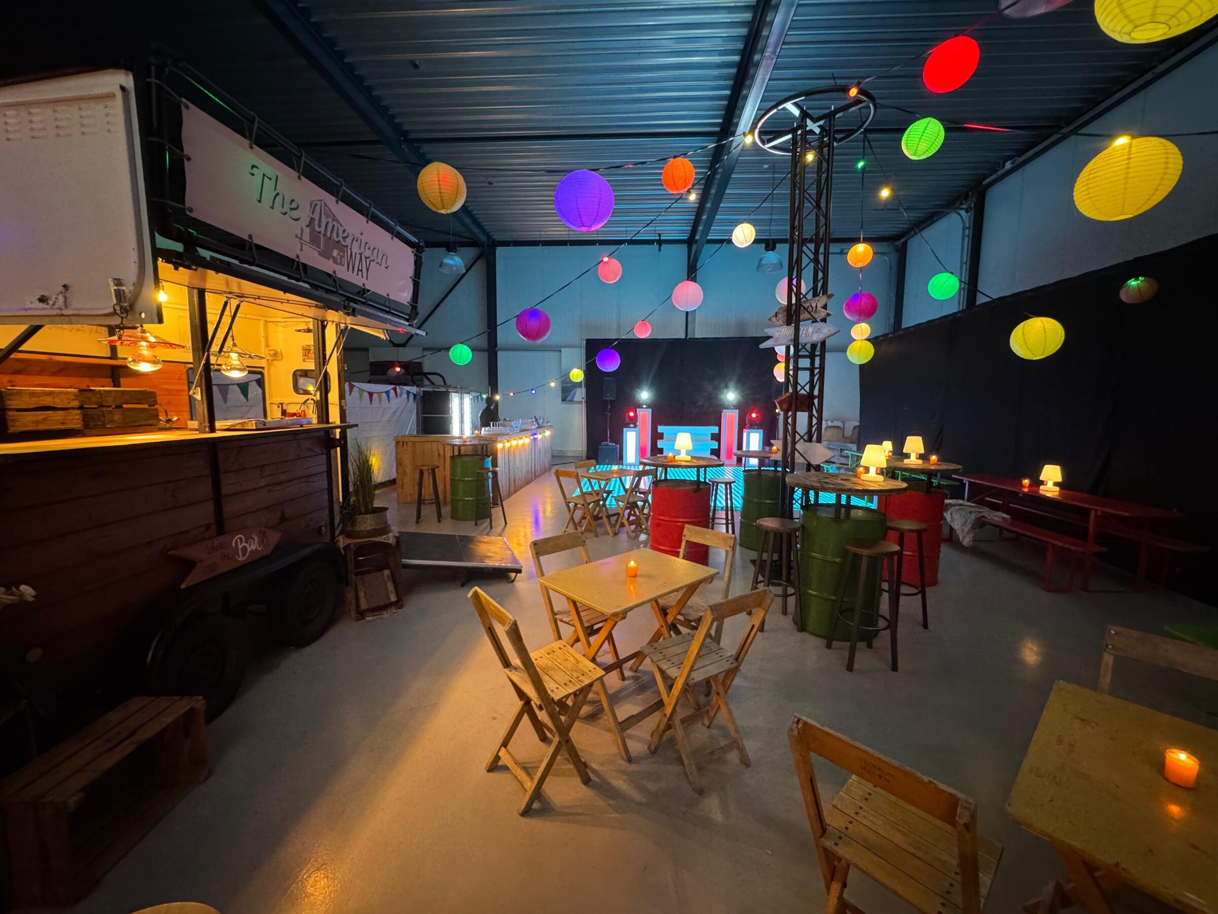 Versierde hangaar met lampionnen, tafel en stoelen en een foodtruck - Timeless Events