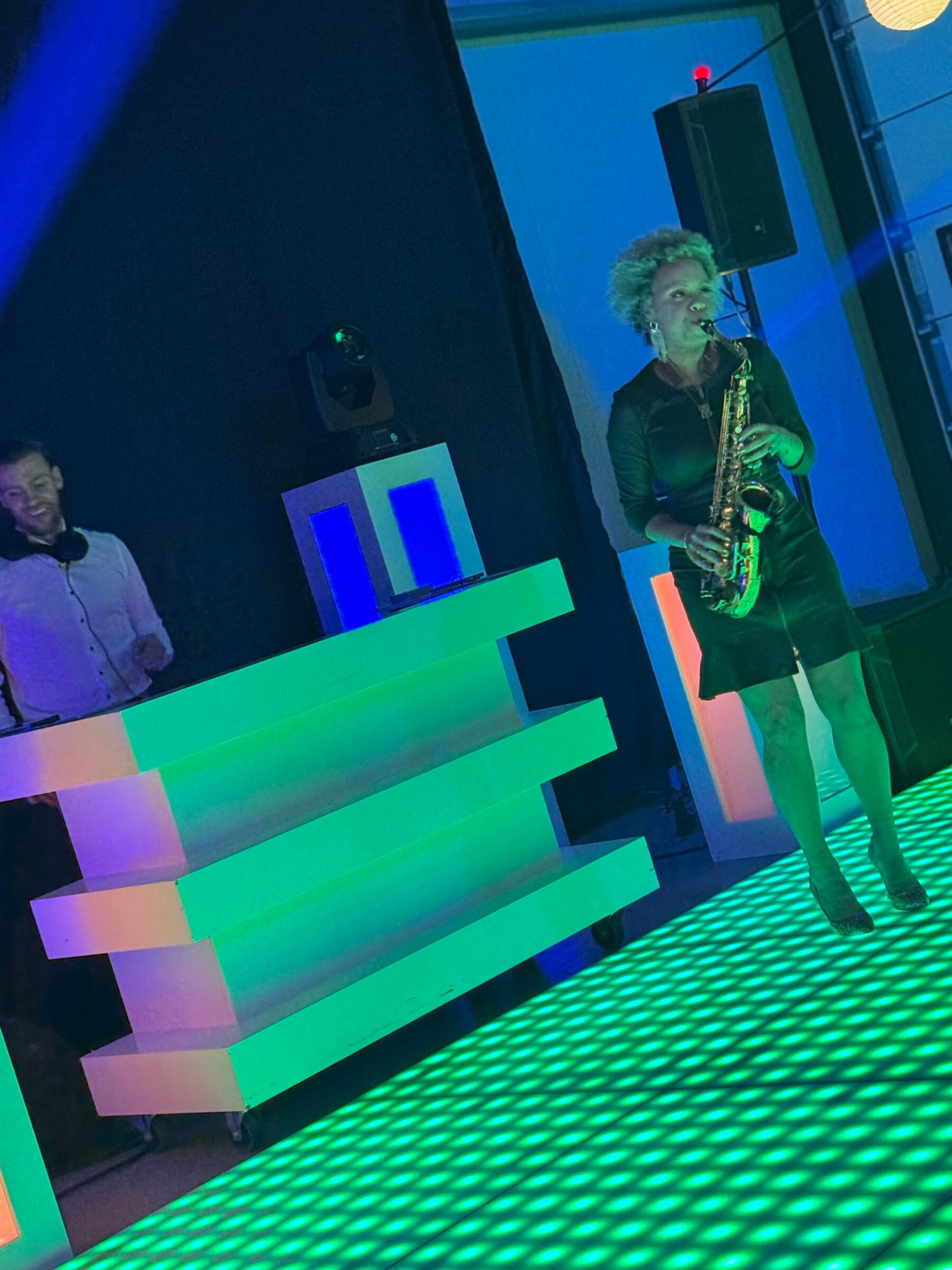 Vrouw blazend op saxofoon op een groen verlichte dansvloer - Timeless Events